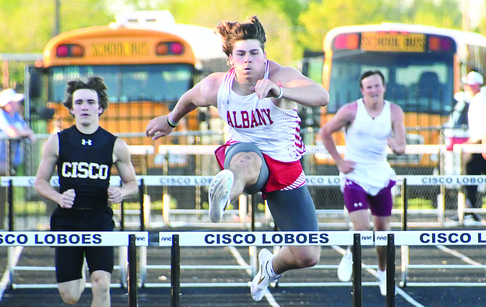 Jayce Tinkle (above, r) hands off to Jaxson Street (l) for the third leg of the varsity boys mile relay at last week’s district track meet in Cisco. Two of the boys relay teams are advancing to today’s area competition. Adam Hill (at left) stays ahead of the pack in the 300m hurdles. He won both hurdles events and was third in the shot put. Eleven Albany athletes are competing in 12 spots at area. Donnie Lucas / Albany News