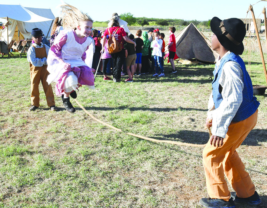 Frontier fun. With Albany principal John Gallagher looking on (above, c) a Living History participant (above, l) hands out wooden rifles to a line-up of students so they learn first-hand about military drills. Some of the younger reenactors (at left) show their skills at jump roping during Friday morning’s School Day at Fort Griffin. Visitors found that hoops and toss games are still fun today. THIS PAGE OF PHOTOS FROM THE 2023 FORT GRIFFIN REENACTMENT IS SPONSORED BY