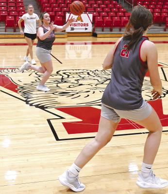 With head girls basketball coach Ashlyn Bevel (l) watching closely in the background, varsity Lady Lion Alli McDaniel (c) throws across the court to teammate Tatum Grady (r) during a Monday afternoon practice. The girls had the district bye on Tuesday, and after a full 11 days since their last game, will face Stamford on Saturday, Dec. in the Bulldog gym. The date was changed because of Stamford’s state football game on Thursday.