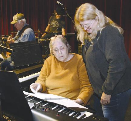 Sandy Abel (l) and performer Kayla McCauley (r) look over music for one of the numbers to be presented at a Nov. 23 musical event. Donn ie Lucas / Albany News