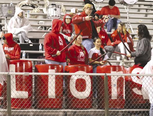 Members of the Ragin’ Red Band and other fans take turns beating the Lion spirit drums at a drizzly area game last Friday night in Springtown. Albany fans are encouraged to gather for the Thanksgiving night pep rally this week, as well as a Friday morning send-off. Photo By Amanda Tabor