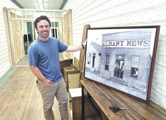 With construction of a new office space behind him, Albany News owner David Waller shows an enlargement of an 1880s-circa photo of The Albany News building. The Wallers plan to move to the downtown space around Dec. 1. They began operation of the newspaper this week. Donnie Lucas / Albany News
