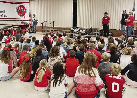 Several members of the Albany Volunteer Fire Departmentspeak to Nancy Smith Elementary classes during the annual fire safety and prevention initiative earlier this month. The children received information packets and toy helmets. Courtesy Photo