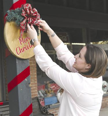 Chamber officer Magaen Birdwell straightens the bow on one of the downtown decorations being put up this week as she and other volunteers get the town ready for the annual Christmas parade on Nov. 25. Lighted entries are being sought for the night-time event. Donn ie Lucas / Albany News