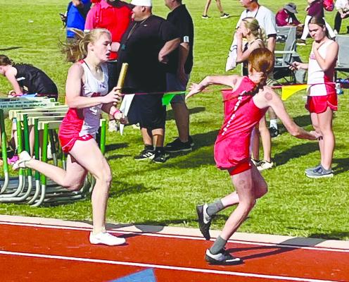 Hailey Gleitz (l) hands off to Tinley Hefner during a seventh grade girls relay at the district track meet on Monday. The meet was cancelled because of lightning, with some field events left unfinished.