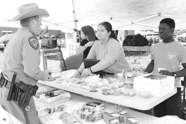 Charlee Patterson (c) and Ben Barwon (r) help Chad Overton with his selections during last Saturday’s youth group bake sale at the Bank Park. Like the car show, the original date was pushed back to May 18 because of bad weather on April 20. Donnie Lucas / Albany News