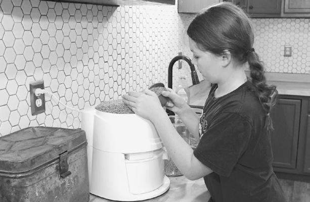 Maggie Spraberry fills her bread making machine as she works on items to be sold at this weekend’s Harvest Acres.