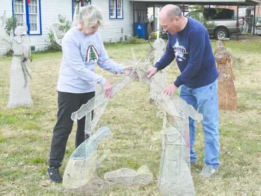 Local homeowners Mary (l) and Cliff (r) Rose work on the positioning of a lighted nativity in their yard earlier this week. One of several local sites nominated in the Chamber of Commerce’s annual house decorating contest, the Rose home will be judged after the Dec. 15 deadline.
