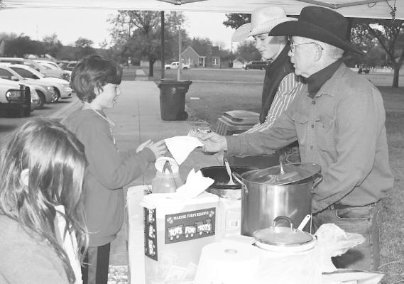 Toys for Tot coordinator Doug Beaty (r) and volunteer Kaiden Cameron (c) serve barbecue sandwiches and bowls of chili during the parade. Proceeds help purchase toys. Donn ie Lucas / Albany News